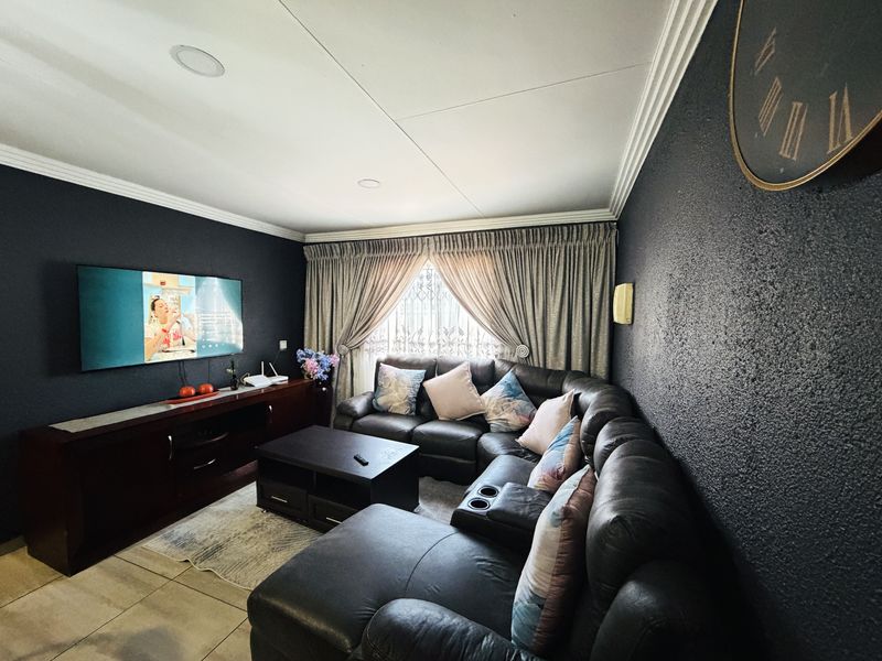 A cozy living room featuring dark textured walls, crown molding, recessed lighting, and tiled flooring, creating a comfortable and intimate entertainment space.
