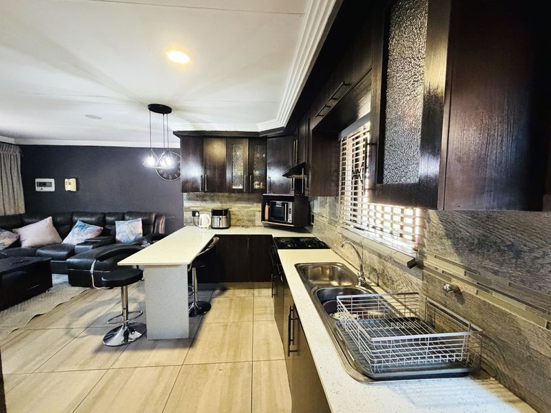 Open plan kitchen and living area featuring dark wood cabinetry, stone countertops, a breakfast bar, and tiled flooring.