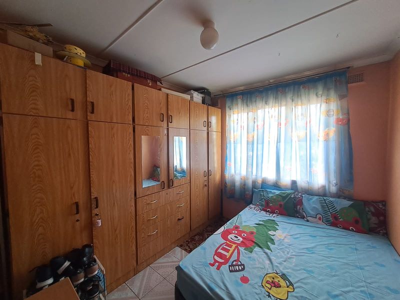 A bedroom featuring extensive built-in wooden cabinetry and tiled flooring, offering ample storage space in a functional, dated layout.