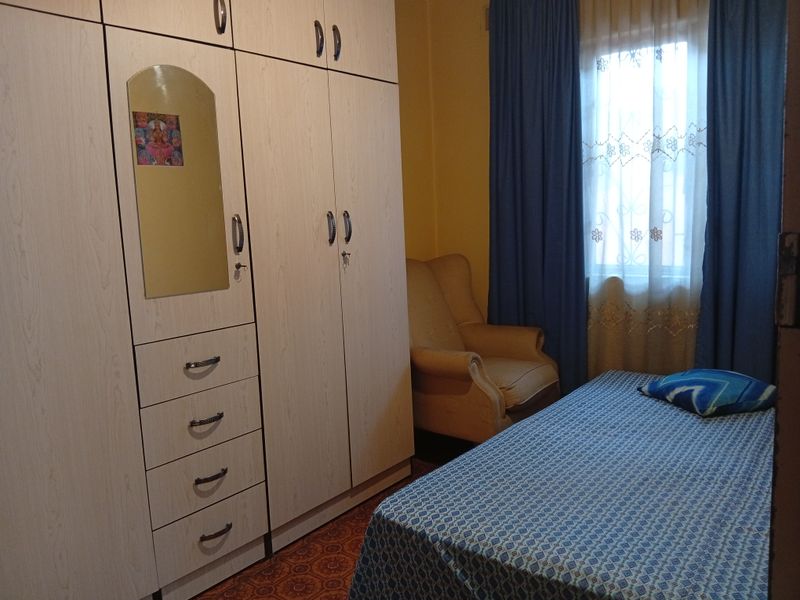 A bedroom featuring extensive built-in wooden cabinetry and a window with curtains, providing functional storage and natural light.