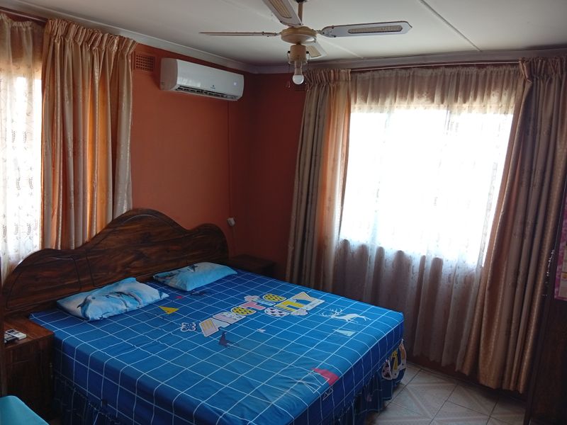 A bedroom featuring tiled flooring, a ceiling fan, and a wall-mounted split-system air conditioner.