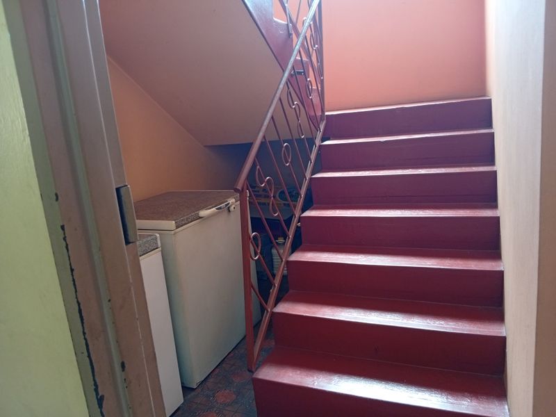 Interior hallway featuring a painted staircase with a metal balustrade and tiled flooring.