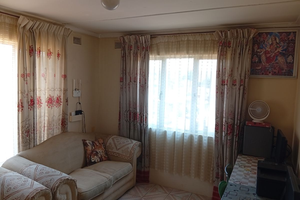 A living room featuring tiled flooring and natural light through windows with installed curtain tracks.