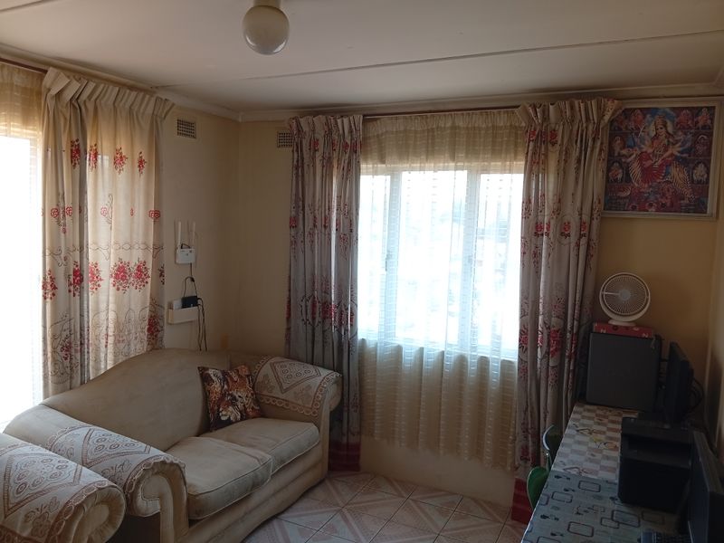 A living room featuring tiled flooring and natural light through windows with installed curtain tracks.