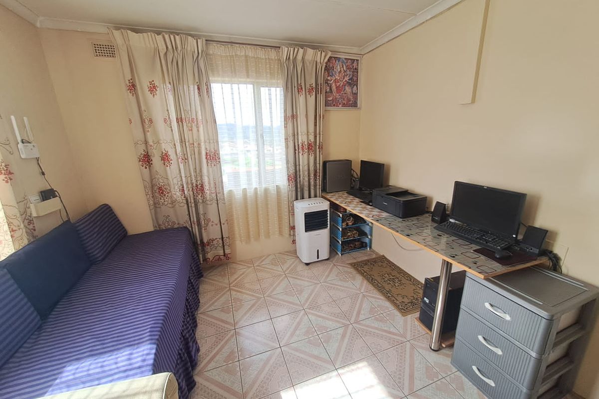 A compact bedroom featuring tiled flooring and a window with curtain tracks, offering a functional space that could benefit from cosmetic updates.