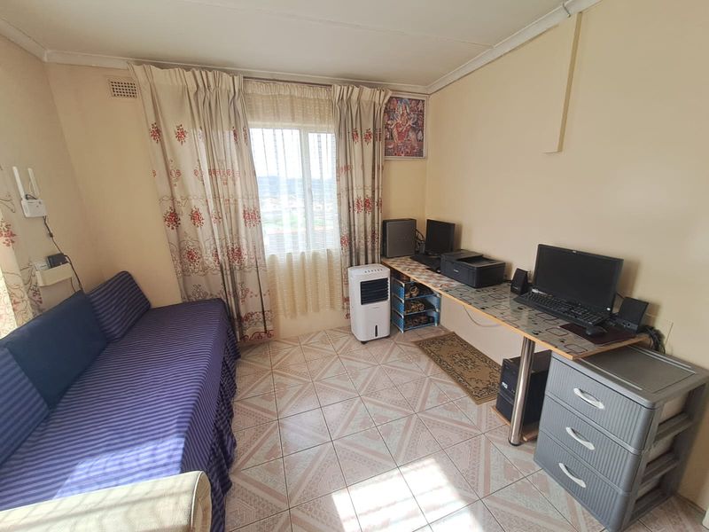 A compact bedroom featuring tiled flooring and a window with curtain tracks, offering a functional space that could benefit from cosmetic updates.