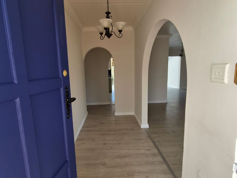 A bright, welcoming entrance hall featuring arched doorways, light-toned laminate flooring, and a classic tongue and groove ceiling.