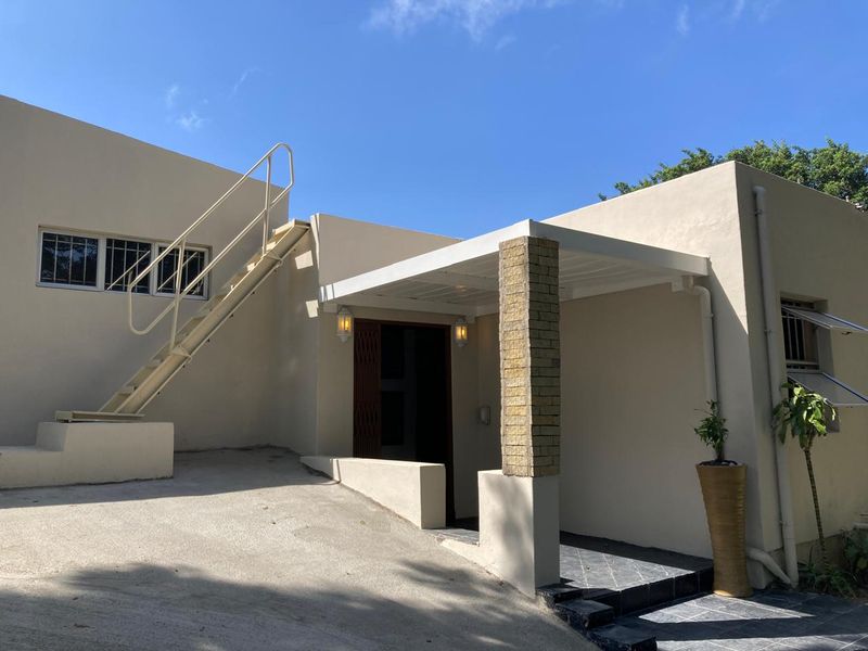 Front exterior view featuring a covered entrance, brick pillar detail, and an external staircase leading to the upper level.