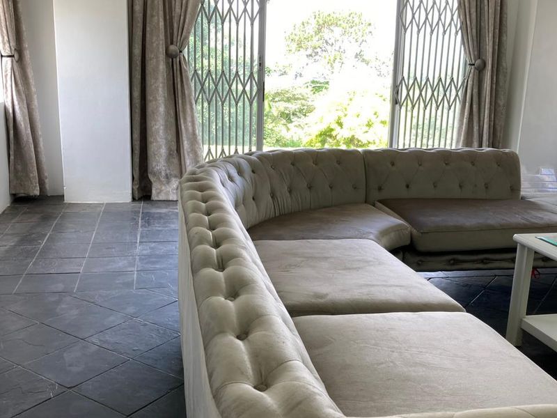 A living room featuring dark slate tile flooring and a large sliding glass door with security gate, providing access to the outdoor area.