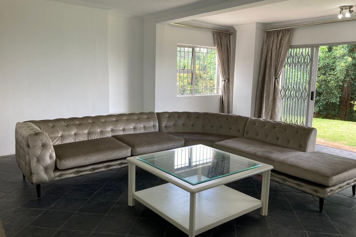 Spacious living room featuring dark tiled flooring, neutral walls, and a sliding glass door providing direct access to the garden.