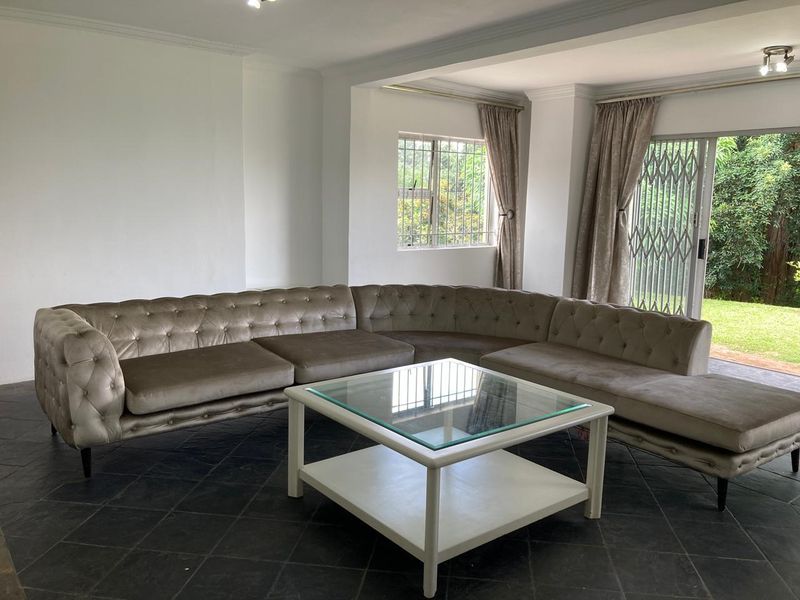 Spacious living room featuring dark tiled flooring, neutral walls, and a sliding glass door providing direct access to the garden.