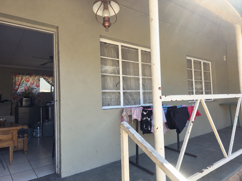 A covered patio area featuring metal railings and support columns, providing access to the interior living space.