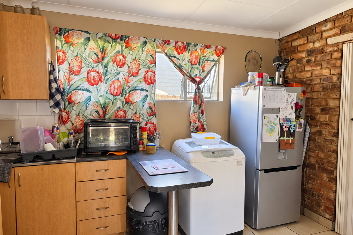 A functional kitchen area featuring laminate cabinetry, a breakfast counter, and a distinctive exposed brick wall, offering potential for modern updates.