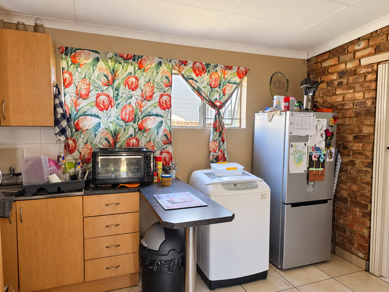A functional kitchen area featuring laminate cabinetry, a breakfast counter, and a distinctive exposed brick wall, offering potential for modern updates.