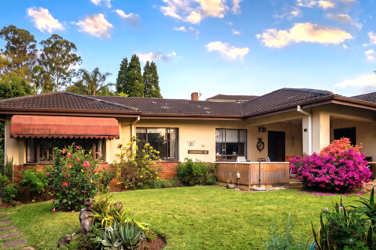 Rear view of the house featuring a landscaped garden, a covered patio area, and a built-in hot tub set against a brick and tile exterior.