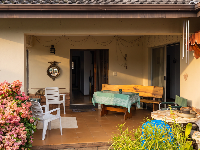 A covered patio area featuring tiled flooring, brick accents, and direct access to the home interior through sliding glass doors.