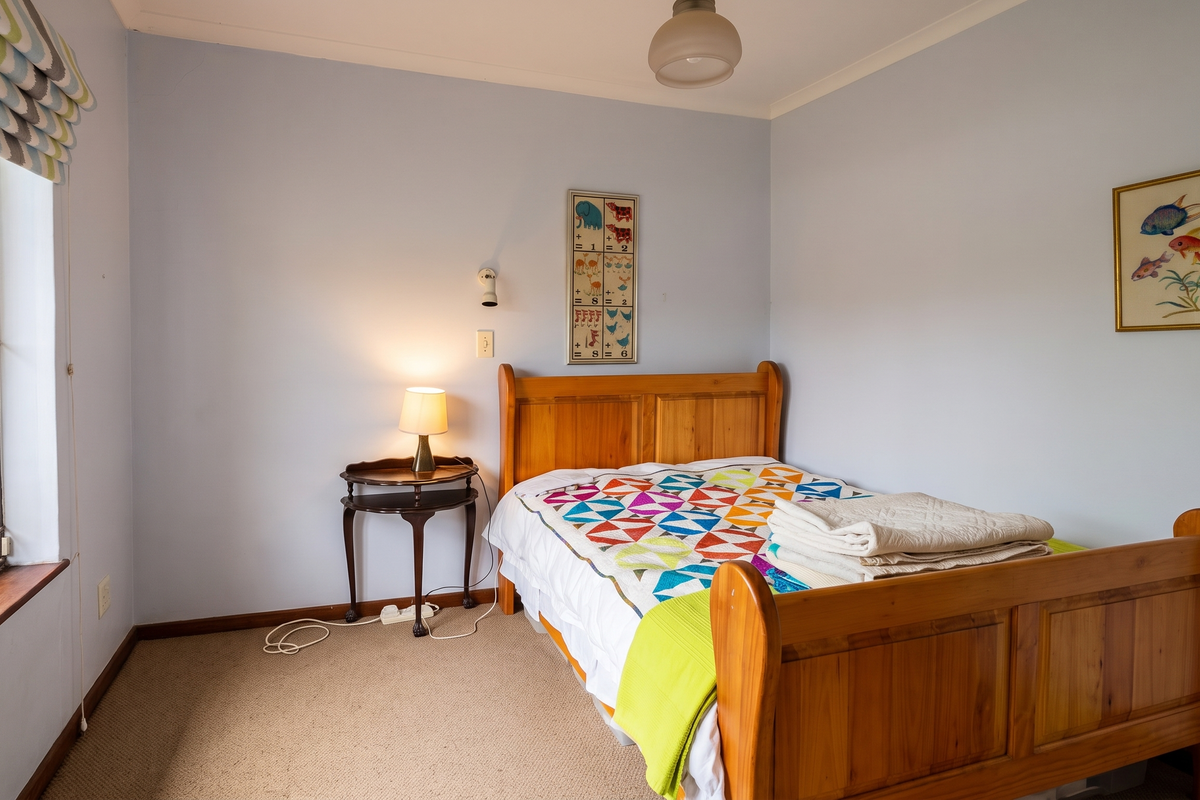 A cozy bedroom featuring carpeted flooring, a window with a security gate, and neutral wall finishes, providing a comfortable and functional living space.