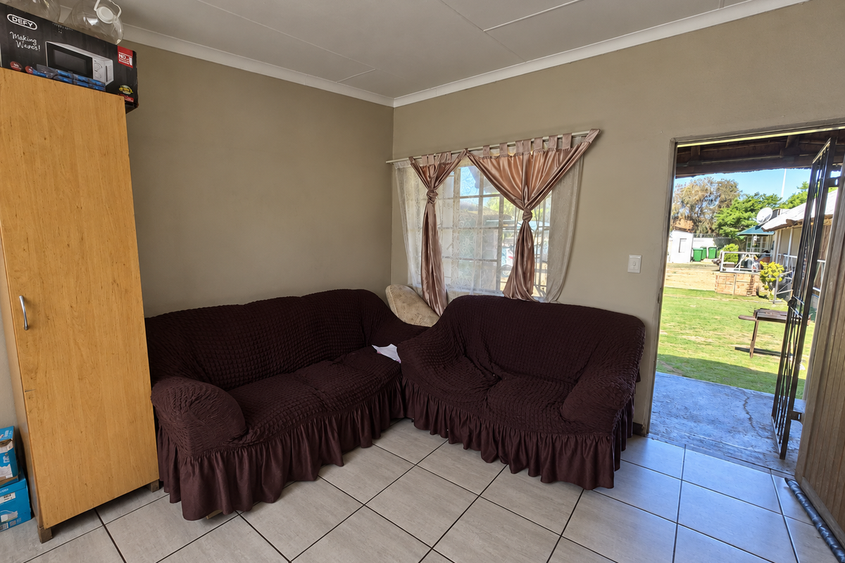 A living room area featuring tiled flooring and direct access to an outdoor garden space through a security gate.