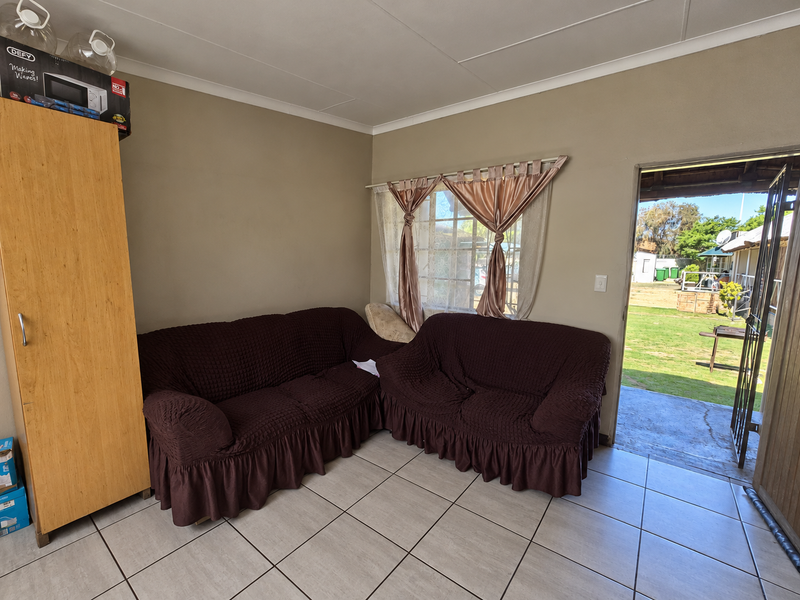 A living room area featuring tiled flooring and direct access to an outdoor garden space through a security gate.