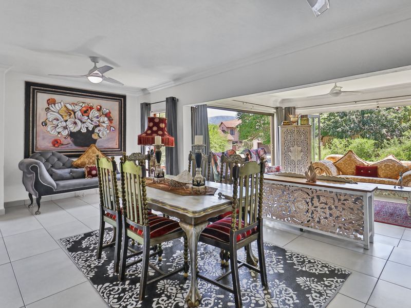 Spacious open-plan living and dining area featuring tiled flooring, ceiling fans, and large sliding glass doors that open to an outdoor patio space.