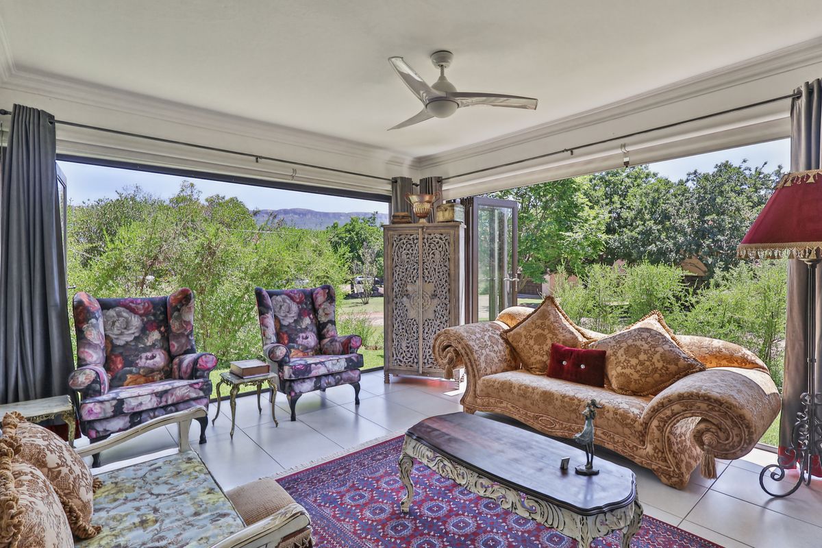 Spacious living area featuring large bi-fold doors that open to a garden view, tiled flooring, and a modern ceiling fan.