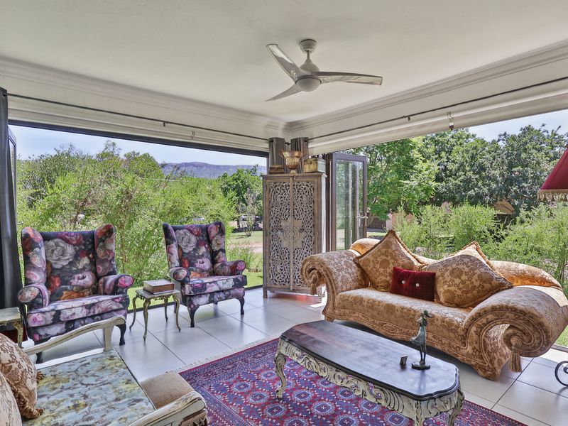 Spacious living area featuring large bi-fold doors that open to a garden view, tiled flooring, and a modern ceiling fan.