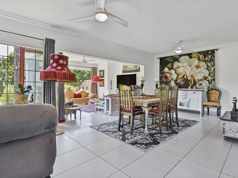 Spacious open-plan living and dining area featuring large format floor tiles, ceiling fans, and sliding glass doors leading to an outdoor patio.