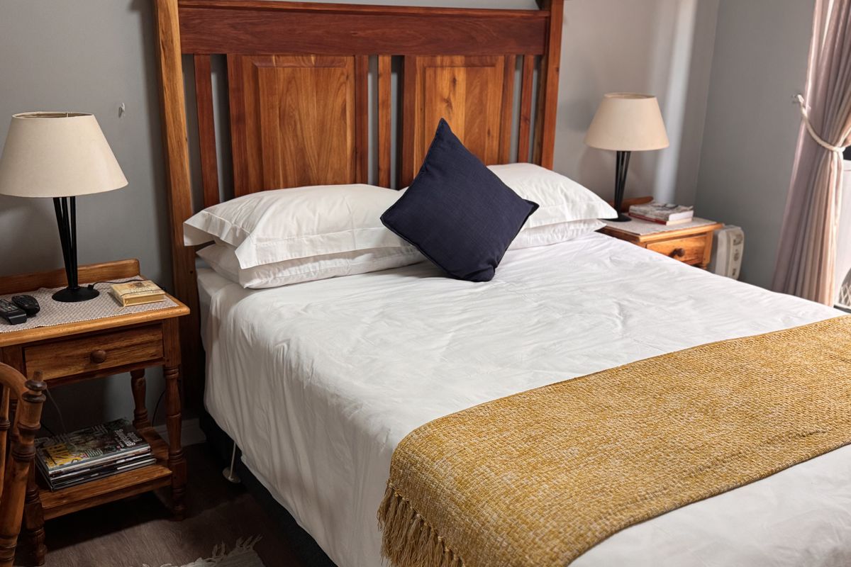 A well-maintained bedroom featuring a wooden headboard and neutral wall tones, providing a comfortable and inviting sleeping space.