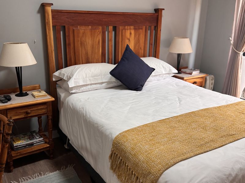 A well-maintained bedroom featuring a wooden headboard and neutral wall tones, providing a comfortable and inviting sleeping space.