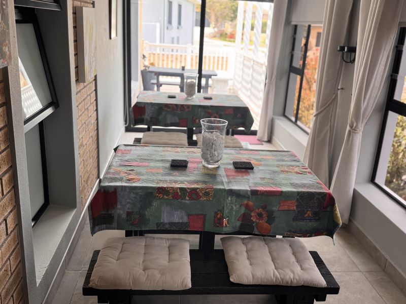 A bright, enclosed patio area featuring exposed brickwork, large windows, and sliding glass doors leading to an outdoor space.
