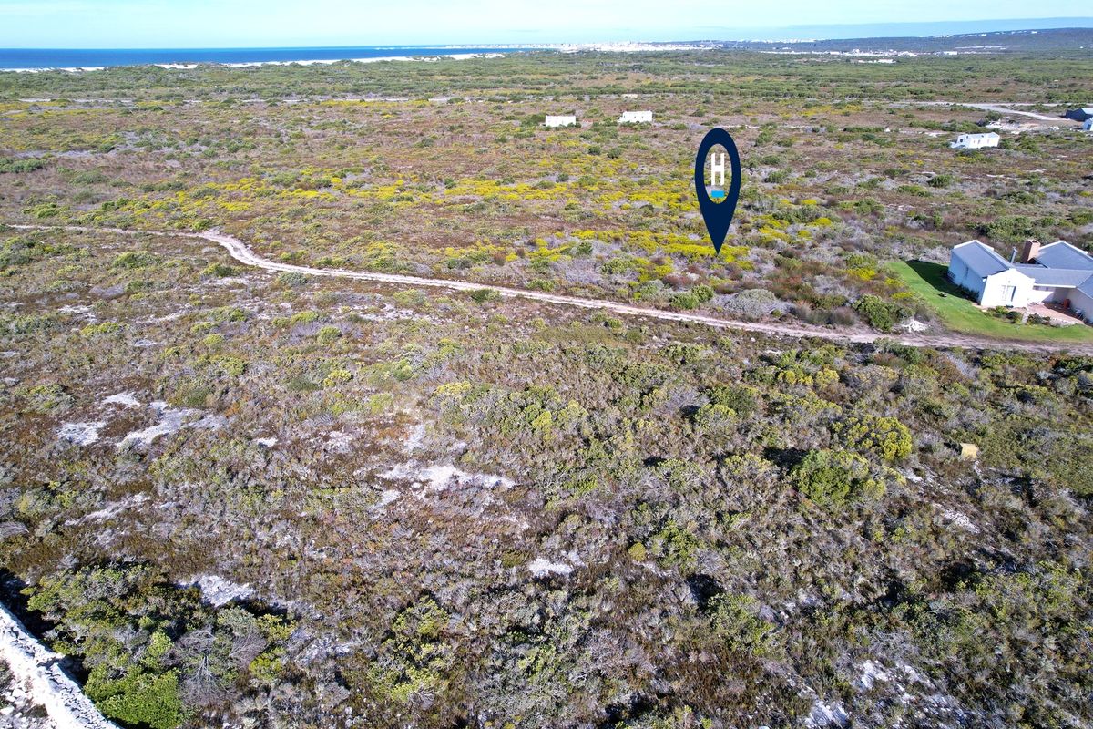 Aerial view of a vacant residential plot featuring native coastal vegetation and an unpaved access track, with distant ocean views.