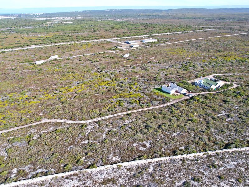 Aerial view of a large residential vacant land plot featuring natural vegetation, gravel access paths, and existing residential structures.