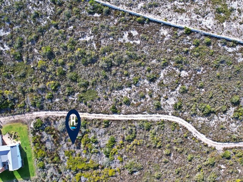 Aerial view of a vacant residential plot featuring native vegetation, a dirt access path, and a stone boundary wall.