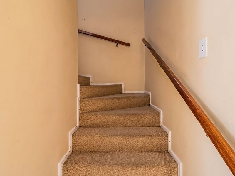A functional staircase featuring carpeted steps and wooden handrails, providing access between levels within the townhouse.