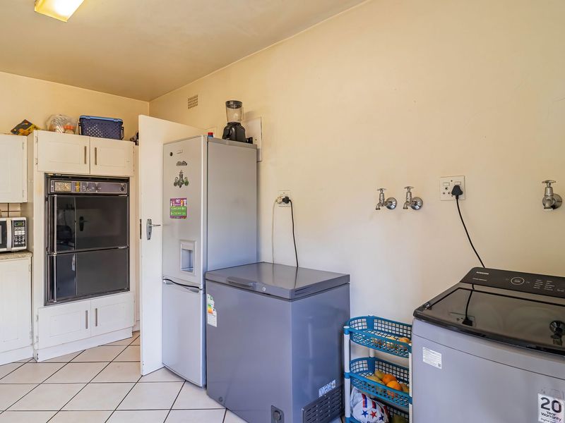 Functional laundry area featuring built-in cabinetry, a double wall oven, tiled flooring, and dedicated plumbing connections for laundry appliances.
