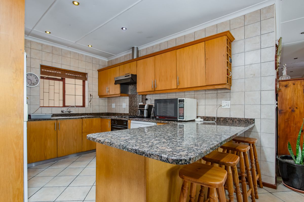 Functional kitchen featuring granite countertops, wooden cabinetry, a breakfast bar, and a tiled backsplash, providing a practical workspace for daily cooking.