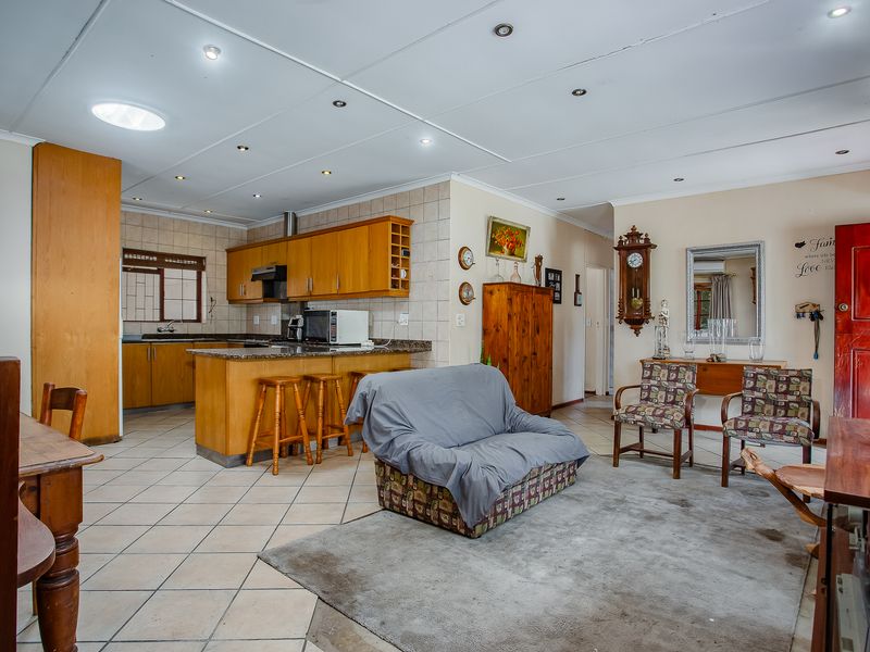 Open-plan living and kitchen area featuring tiled flooring, recessed lighting, a skylight, and wooden cabinetry with granite countertops.