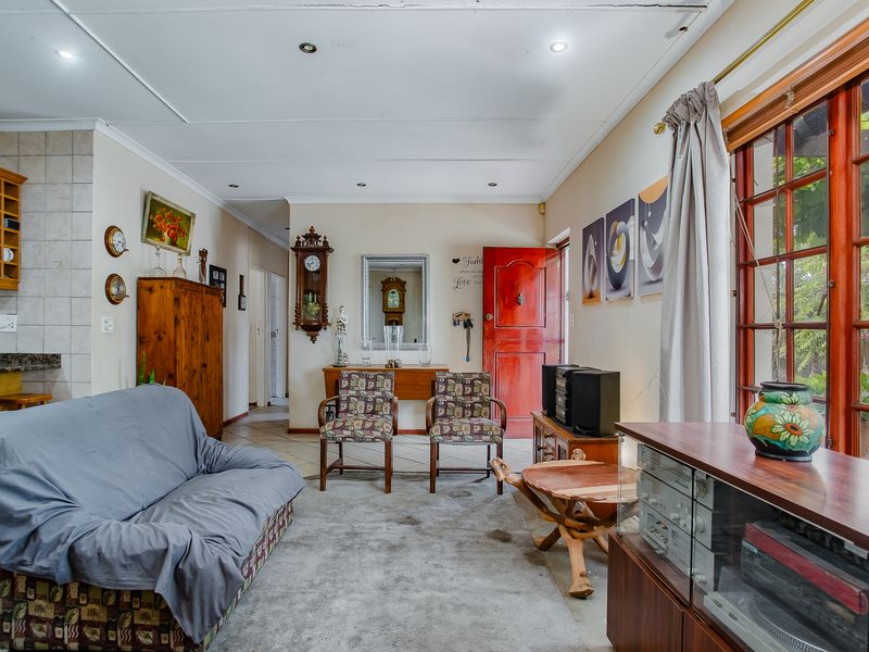 A living room featuring tiled flooring, recessed ceiling lighting, and timber-framed windows providing natural light and access to the exterior.