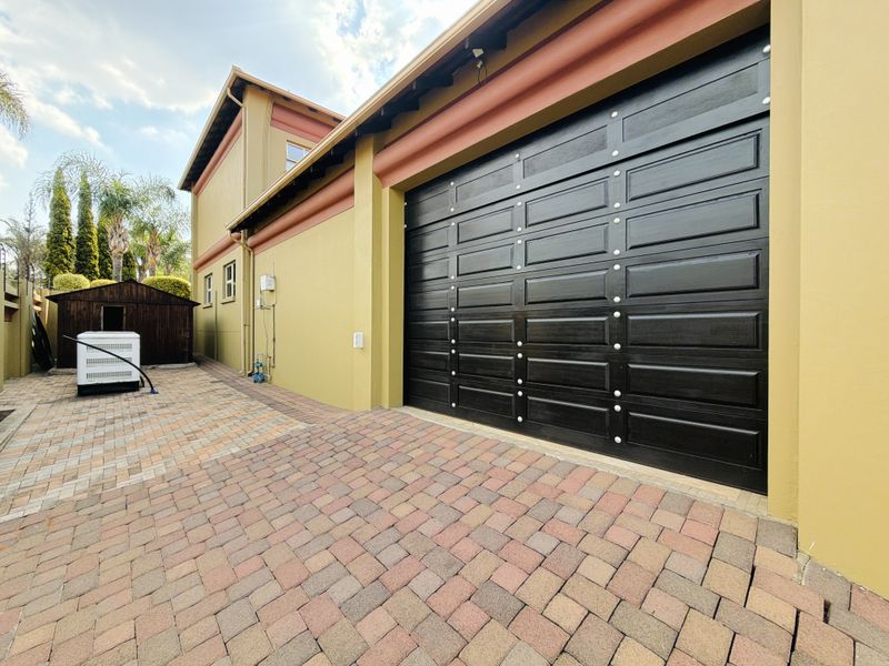 Exterior view of a double garage with a modern black sectional door and paved driveway area.