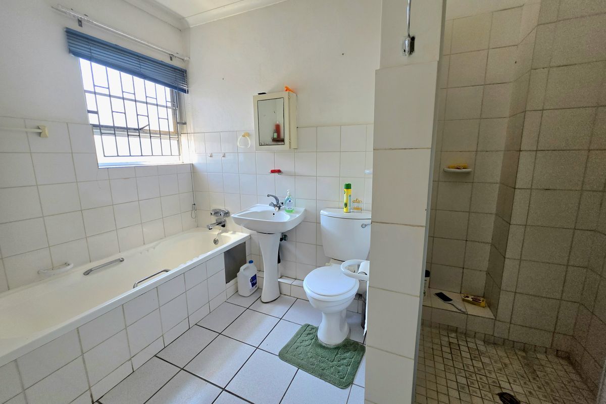 A functional bathroom featuring a bathtub, pedestal basin, toilet, and separate shower enclosure with tiled finishes throughout.