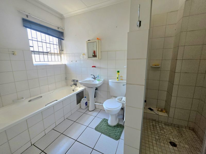 A functional bathroom featuring a bathtub, pedestal basin, toilet, and separate shower enclosure with tiled finishes throughout.
