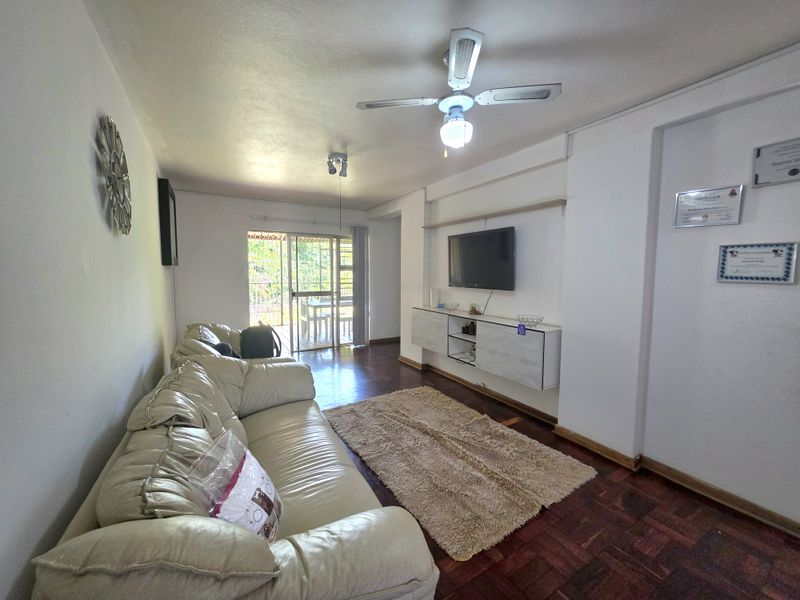 A living room featuring parquet flooring, a ceiling fan, and wall-mounted cabinetry, with direct access to an outdoor patio area through sliding glass doors.