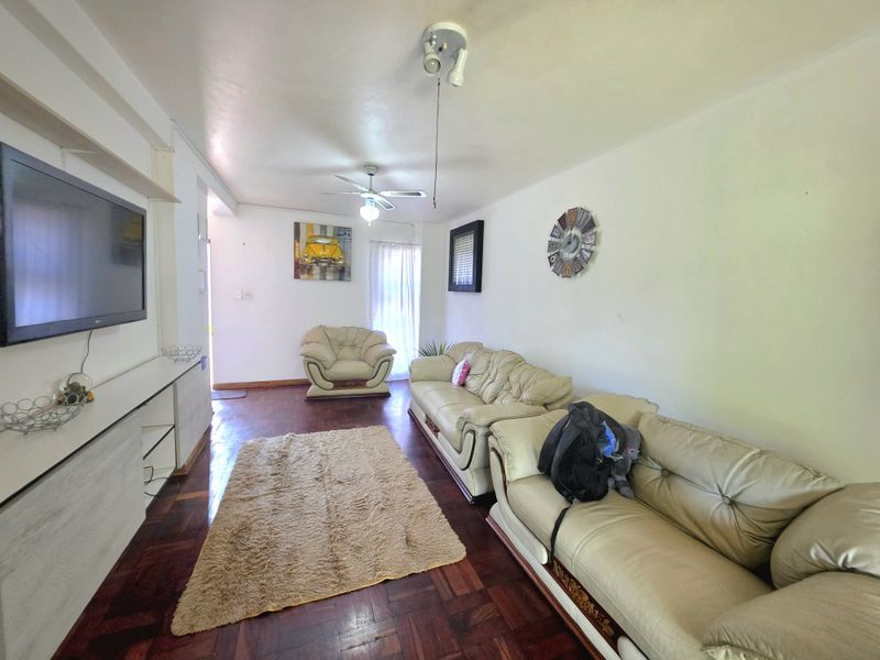 A living room featuring dark parquet flooring, a ceiling fan, and a built-in media console unit.