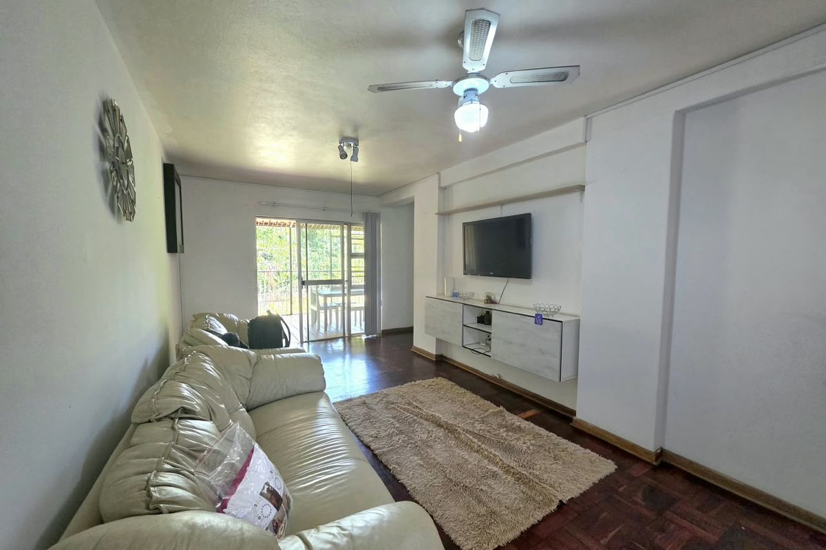 Living room featuring parquet flooring, a ceiling fan, and wall-mounted cabinetry, with direct access to an outdoor patio area through sliding glass doors.