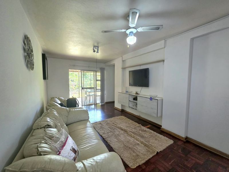Living room featuring parquet flooring, a ceiling fan, and wall-mounted cabinetry, with direct access to an outdoor patio area through sliding glass doors.