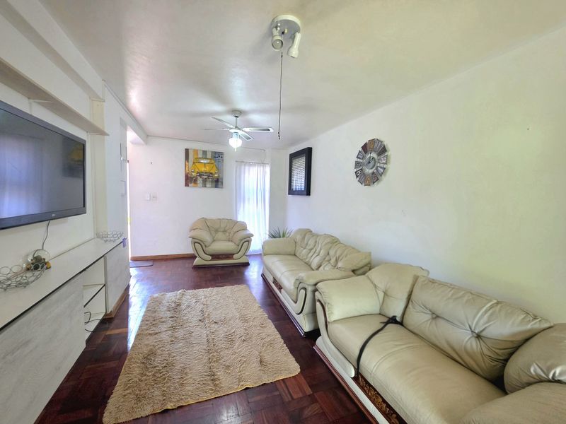 A living room featuring dark parquet flooring, a ceiling fan, and a built-in media console unit.