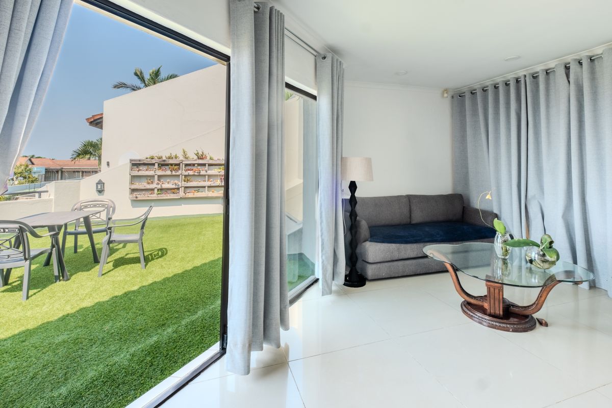 Bright living room featuring large sliding glass doors that provide seamless access to an outdoor patio area with artificial turf.