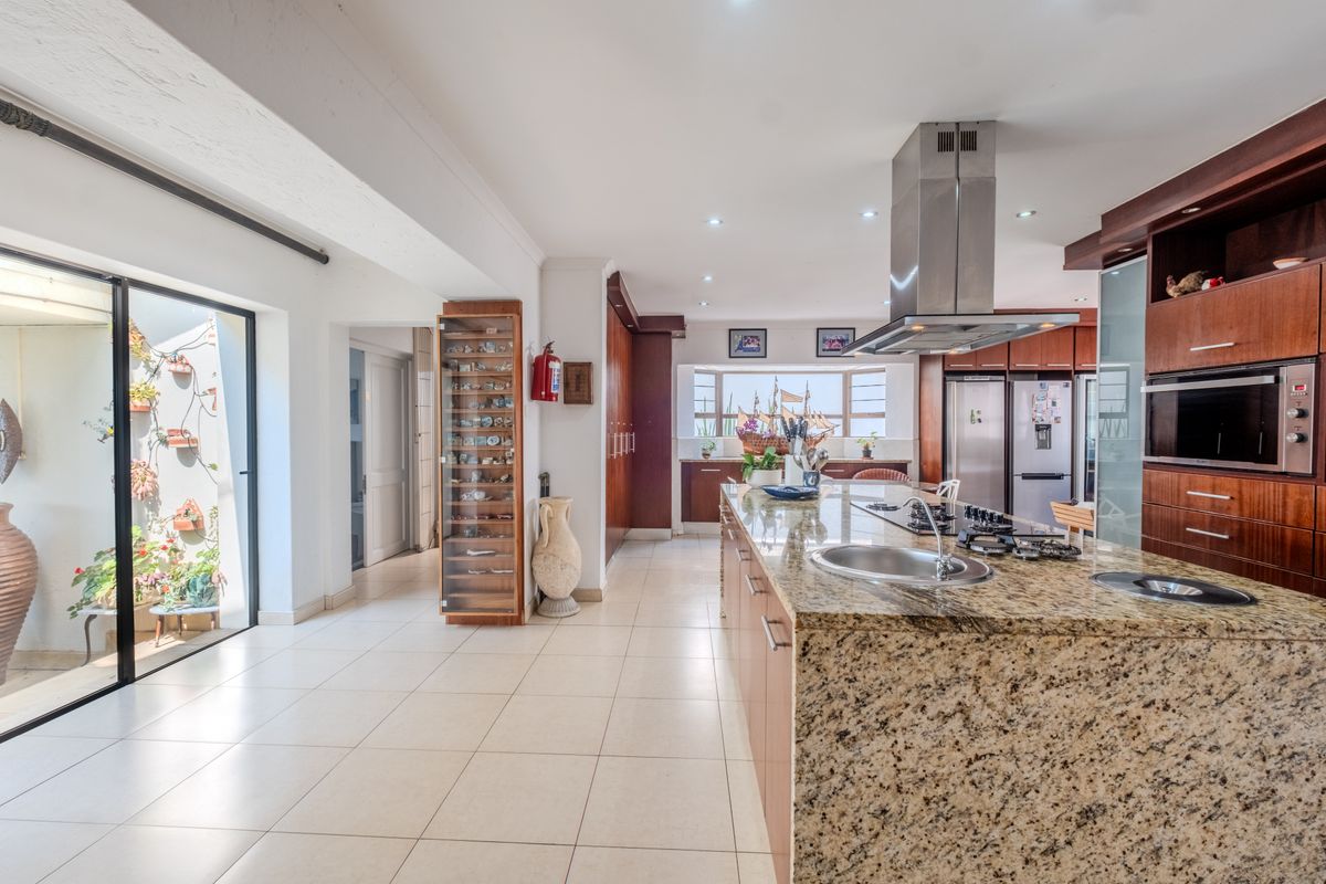 Spacious kitchen featuring a large granite-topped island, built-in stainless steel appliances, ample cabinetry, and direct access to an outdoor patio area.