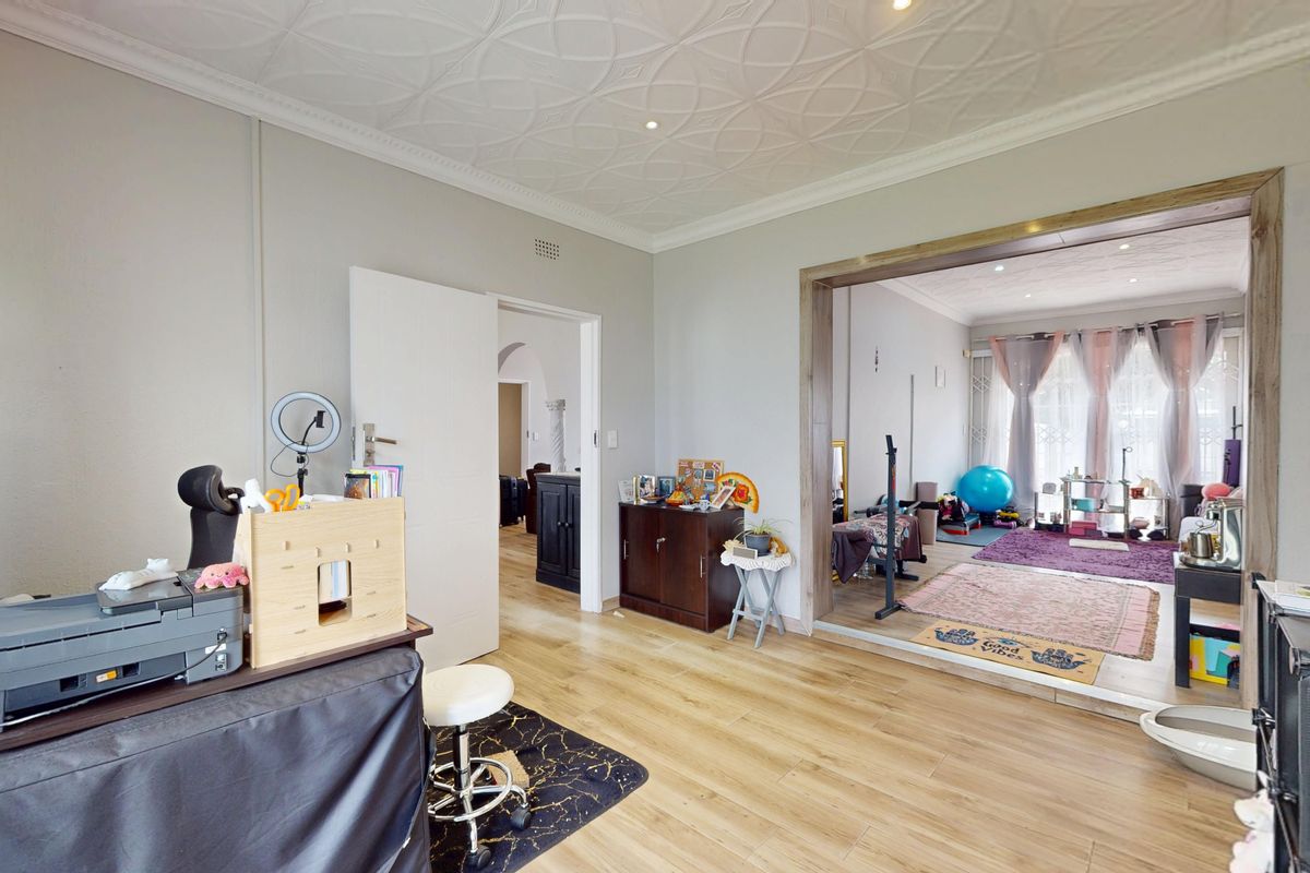 Spacious living area featuring laminate flooring and a decorative ceiling, with an open-plan flow into an adjacent room.