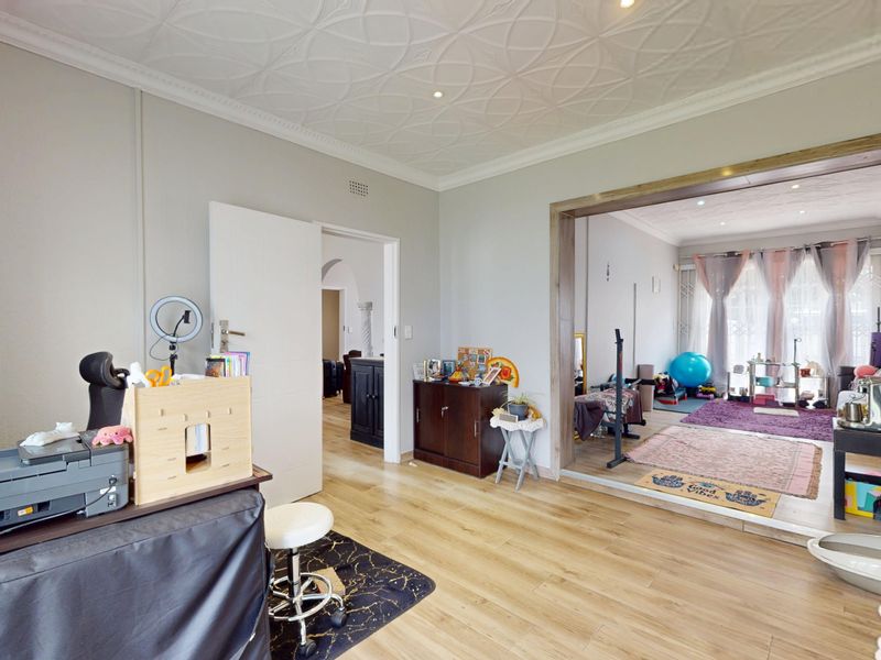 Spacious living area featuring laminate flooring and a decorative ceiling, with an open-plan flow into an adjacent room.